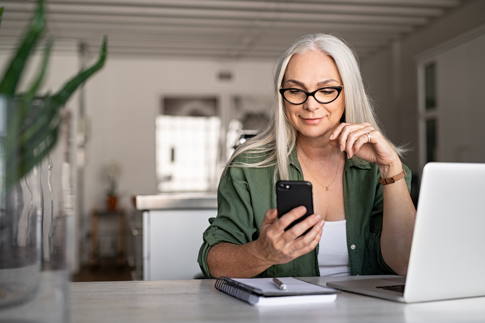 Woman working on laptop and phone at home